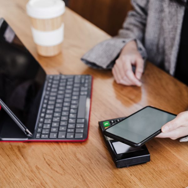 Vrouw zit aan een tafel met een tablet en telefoon